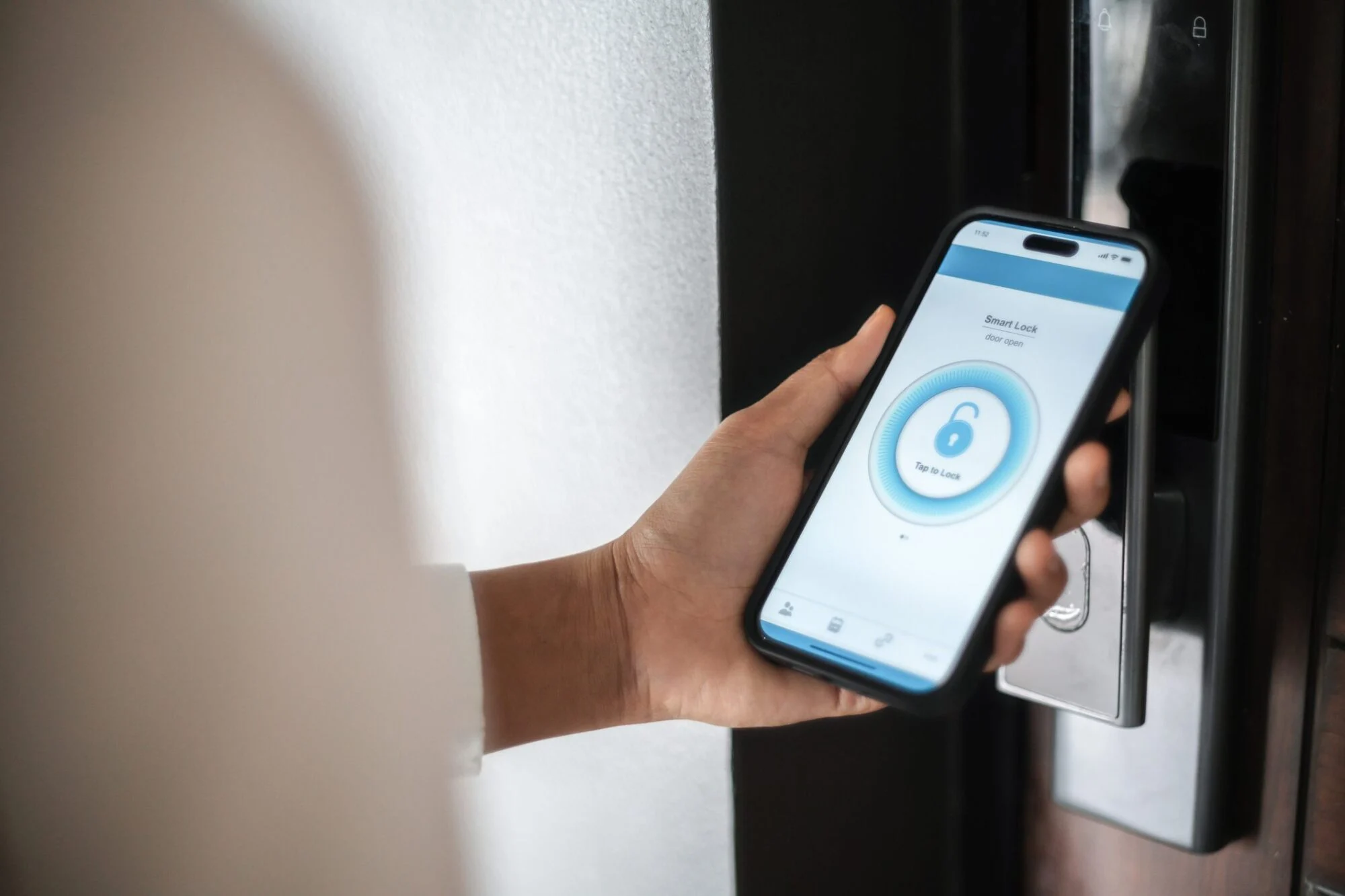 A person uses a smartphone app to unlock a door with a smart lock.