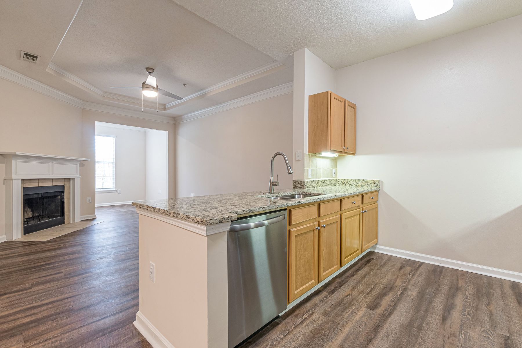 Empty room with wood floors, ceiling fan, and sliding glass door leading to a patio with vertical blinds at Apex West Midown.